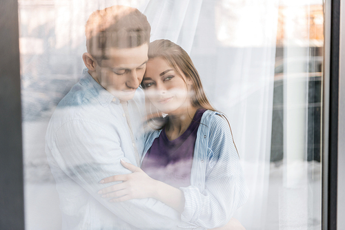 view through window on couple hugging and looking away