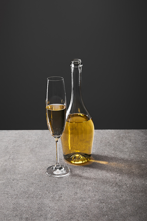 glass and bottle of sparkling wine on grey