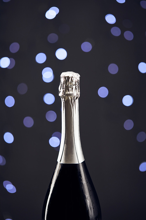 close up of sparkling wine bottle with blue christmas lights bokeh