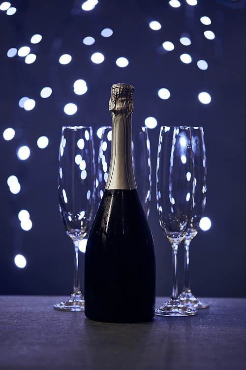 bottle of sparkling wine and glasses with blue christmas lights bokeh