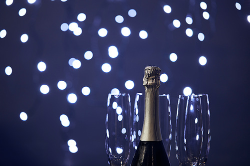 bottle of sparkling wine and glasses with blurred christmas lights