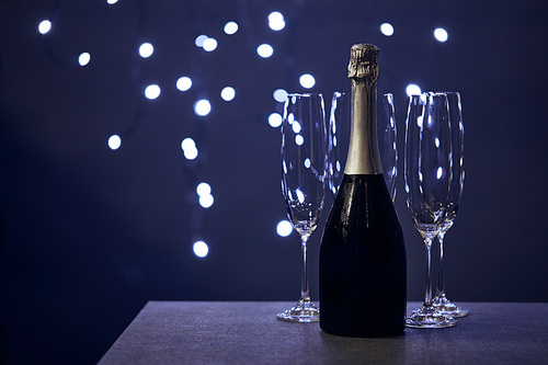 bottle of champagne and glasses with blurred christmas lights