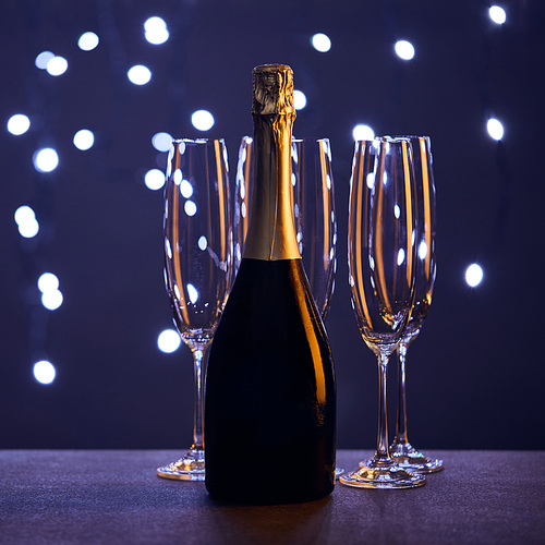 bottle of champagne and glasses with christmas lights bokeh