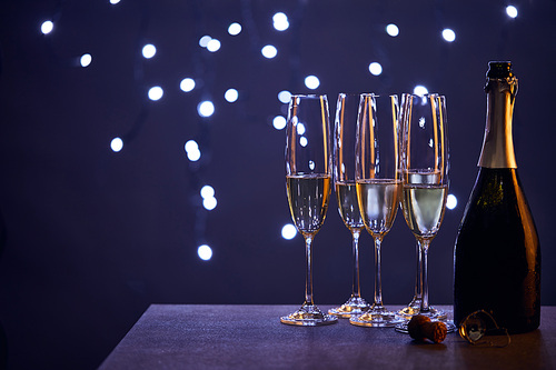 champagne in bottle and glasses with blue christmas lights bokeh