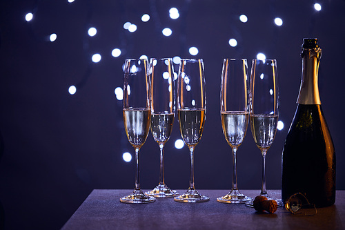 Sparkling wine in bottle and glasses with blue christmas lights bokeh