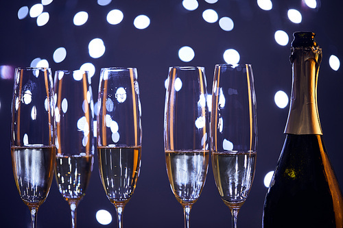 Sparkling wine in bottle and glasses with blurred blue christmas lights