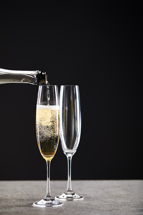 champagne pouring from bottle into glasses for celebrating christmas on black