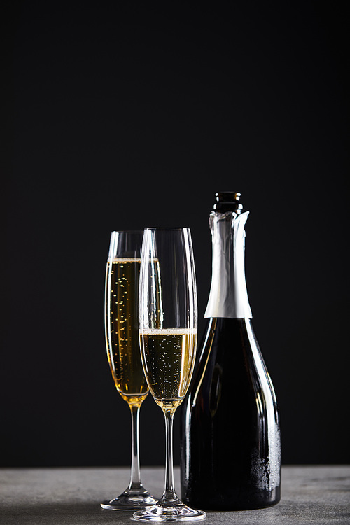 glasses and bottle of sparkling wine for celebrating christmas on black