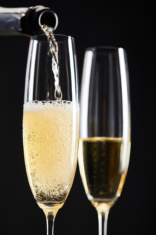 close up of champagne pouring into glasses for celebrating christmas, isolated on black