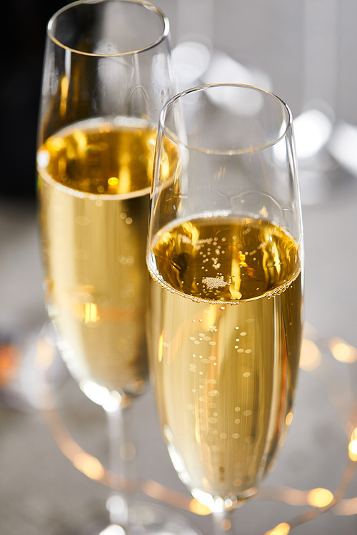 close up of glasses of sparkling wine with blurred yellow christmas lights