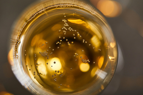 top view of sparkling wine in glass with blurred yellow christmas lights