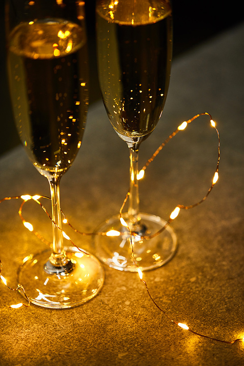 traditional sparkling wine in glasses with yellow christmas lights