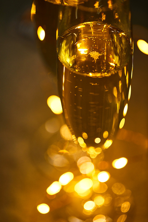 close up of glasses of sparkling wine with blurred yellow christmas lights