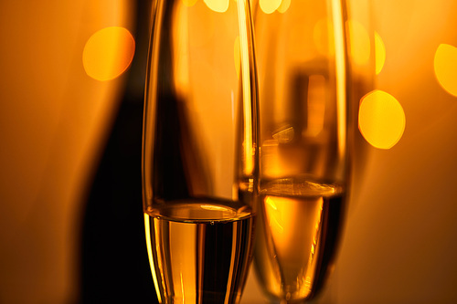 glasses of sparkling wine with blurred bottle and yellow christmas lights