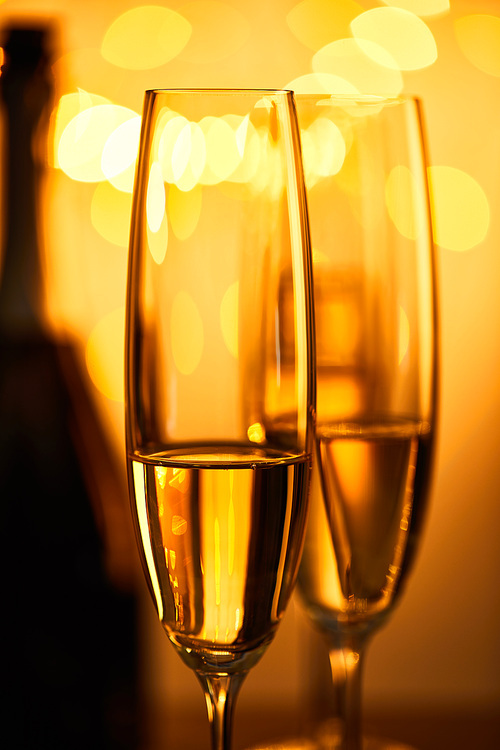 glasses of champagne with blurred bottle and yellow christmas lights