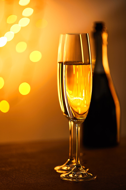 glasses of champagne with blurred bottle and yellow christmas lights