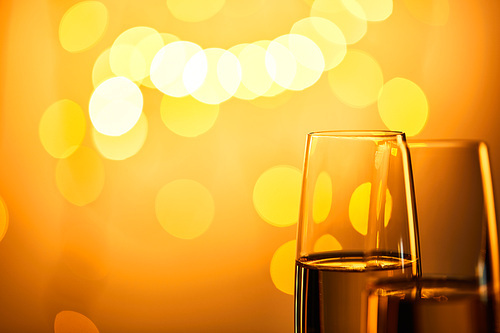 close up of glasses of champagne with yellow christmas lights bokeh