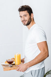 handsome man holding wooden tray with breakfast and 