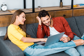 young attractive girl showing something on laptop to smiling boyfriend