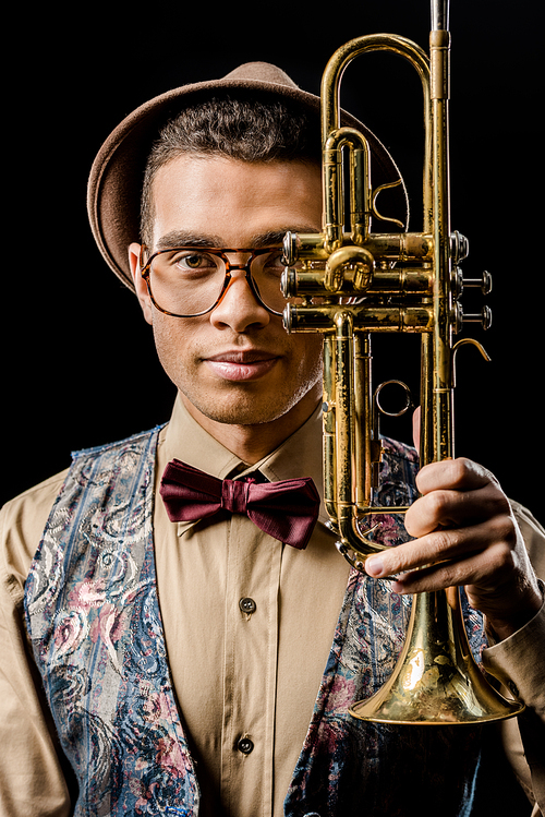 portrait of stylish young male musician posing with trumpet isolated on black