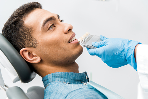 handsome african american man smiling near teeth color palette before whitening procedure