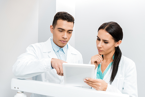 serious multiethnic doctors looking at digital tablet