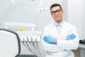 handsome african american dentist in glasses standing with crossed arms