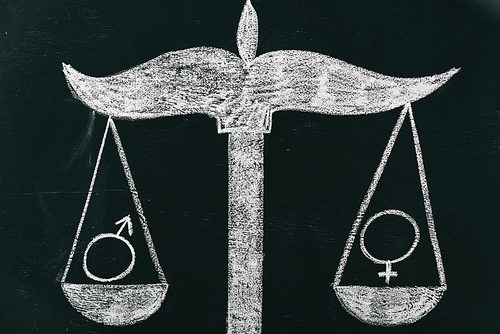 male and female signs on scales drawing on chalkboard, gender equality concept