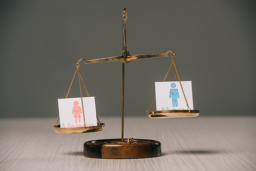 male and female signs on scales on wooden table, gender equality concept