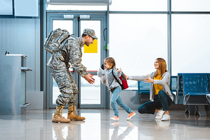 happy daughter running to father in military uniform in airport