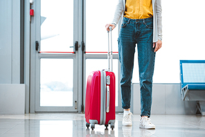 cropped view of woman standing with baggage in airport