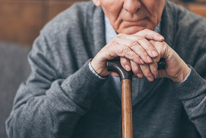 cropped view of upset retired man with walking cane