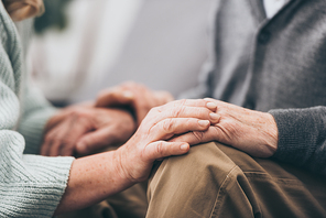 cropped view of retired couple holding hands