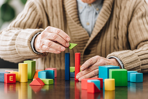 cropped view of retired man playing with wooden toys on table
