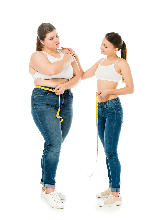 slim woman supporting sad overweight woman with measuring tape isolated on white