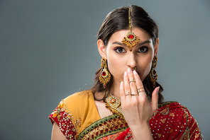 surprised indian woman closing mouth, isolated on grey