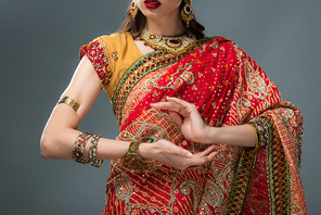 cropped view of attractive indian woman gesturing in traditional clothing, isolated on grey