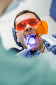 selective focus of patient with opened mouth during bleaching procedure near dentist