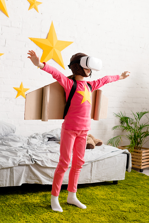 Full length view of kid in vr headset waving hands in bedroom