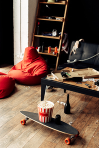 skateboard with popcorn box near coffee table in messy living room