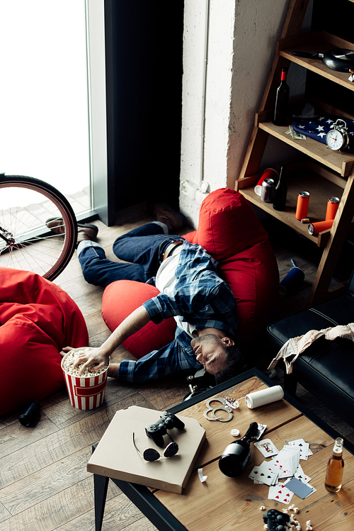 drunk man lying on bean bag and taking popcorn from popcorn box