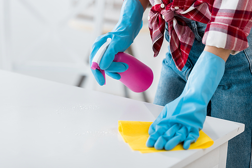 cropped view of african american woman cleaning table in blue rubber gloves