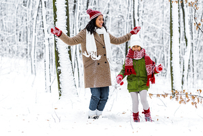 beautiful african american woman and cute preteen daughter having fun in winter park