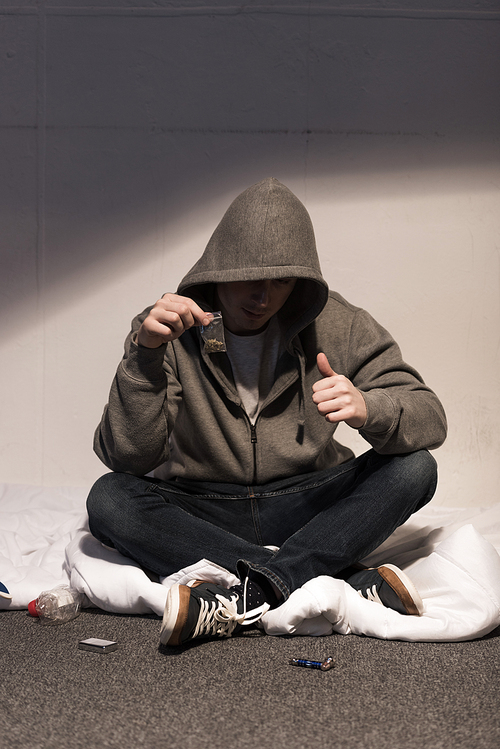 junkie man holding pack of marijuana and showing thumb up