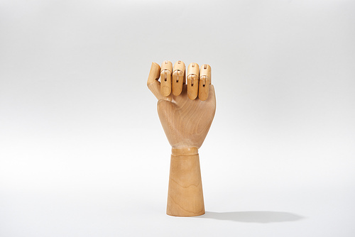 Hand of wooden doll in fist on grey background