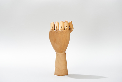 Hand of wooden doll with shadow on grey background
