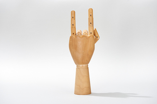 Wooden hand of doll with rock symbol on grey background