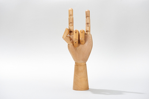 Wooden hand of puppet with rock gesture on grey background