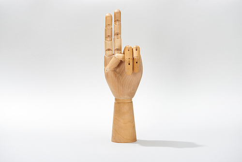 Wooden hand of doll with peace sign on grey background