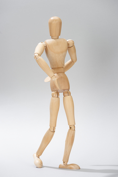 Wooden puppet with hinges on grey background